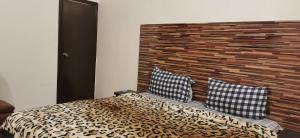 a bedroom with a bed with a wooden headboard and two pillows at Hotel Elegant Near Karachi Expo Center and Agha Khan in Karachi