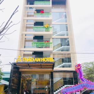 フエにあるTHẢO AN HOTEL Huếの看板が目の前にある高層ビル