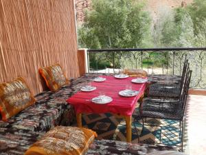 a red table and chairs on a balcony at Auberge Kasbah Ait Marghad in Tamellalt
