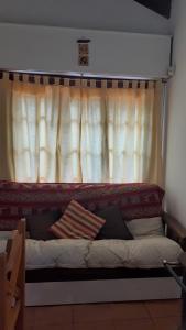 a bed in front of a window with a curtain at Cabaña Paso a Paso in Tandil
