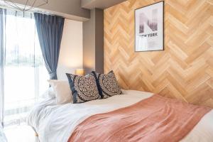 a bedroom with a bed with a wooden wall at Bijou Suites Bloom in Osaka