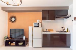 a kitchen with a white refrigerator and a tv at Bijou Suites Bloom in Osaka