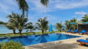 a resort swimming pool with blue chairs and palm trees at Andalay Boutique Resort in Ko Lanta