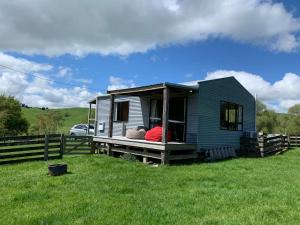 a person sitting on the porch of a tiny house at Fallow Hut in Masterton
