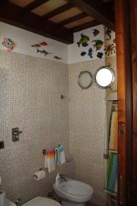 een badkamer met een toilet en een wastafel met vis aan de muur bij Casa Claudia in Marsala