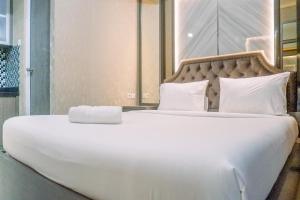 a large bed with white sheets and pillows at Classic Studio Room Apartment at Taman Melati Surabaya By Travelio in Surabaya