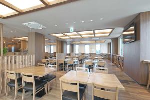 uma sala de jantar com mesas e cadeiras de madeira em Hotel Route Inn Kusatsu Ritto -Ritto Inter Kokudo 1 gou- em Ritto