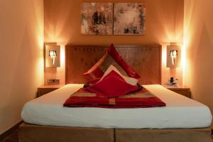 ein Schlafzimmer mit einem großen Bett mit roten Kissen in der Unterkunft Hotel Blauer Engel in Aue