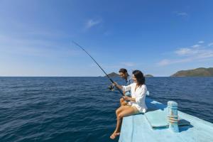a man and a woman sitting on a boat fishing at Six Senses Con Dao - Turtle Island Paradise in Con Dao