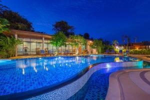 una gran piscina por la noche en The Tama Hotel- SHA Plus, en Ao Nam Mao