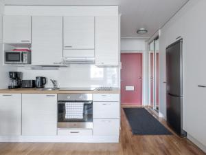 a kitchen with white cabinets and a stainless steel refrigerator at Kotimaailma Apartments Joensuu - Koulukatu 21 in Joensuu