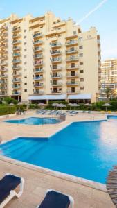 a large swimming pool in front of a large building at Club Amarílis,Alex&Mila Aparthotel Praia da Rocha in Portimão