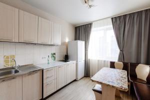 ケメロヴォにあるAvant Apartment Svobody 19のキッチン(白いキャビネット、テーブル、冷蔵庫付)