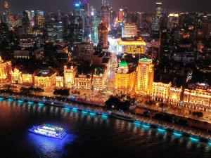 un barco en el agua con una ciudad por la noche en Fairmont Peace Hotel On the Bund en Shanghái
