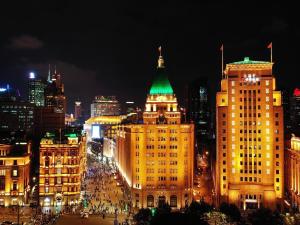 a city lit up at night with a green roof at Fairmont Peace Hotel On the Bund in Shanghai