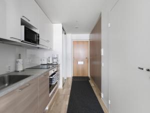 eine Küche mit weißen Wänden und Holzschränken in der Unterkunft Kotimaailma Apartments Joensuu - Kalevankatu 36 in Joensuu