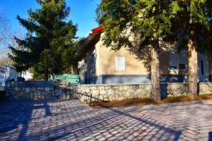a house with a stone wall and trees in front of it at Pellegrini Apartman in Balatonakali