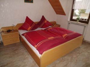 ein Bett mit roter Bettwäsche und roten Kissen im Schlafzimmer in der Unterkunft Weingut-Gästehaus Karl Otto Nalbach in Briedel