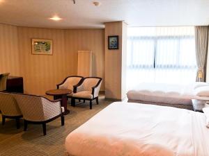 Habitación de hotel con 2 camas, mesa y sillas en Honey Moon Hotel en Renai