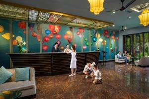 una mujer y dos niños en un vestíbulo con una pared con globos en Bel Marina Hoi An Resort, en Hoi An