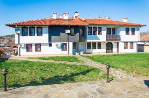 a large house with a green yard in front of it at Family Hotel Elegance in Arbanasi