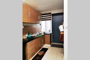 eine Küche mit Holzschränken und einer schwarzen Arbeitsplatte in der Unterkunft Bintang Maya Residence cozy and comfortable stay in Sungai Petani