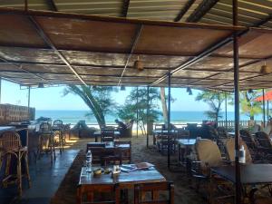 a restaurant with tables and chairs and a view of the ocean at Peace Garden Beach Resort in Canacona