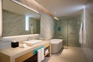 uma casa de banho com um lavatório, uma banheira e um espelho. em Holiday Inn Tianjin Xiqing, an IHG Hotel em Tianjin
