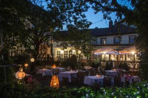 un restaurant avec des tables blanches et des lumières devant un bâtiment dans l'établissement Hotel Krone, à Hirschberg an der Bergstraße