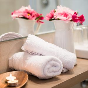 a pile of towels and a vase with flowers at Hostal Menurka in Ciutadella