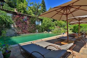 einen Pool mit Stühlen und Sonnenschirmen neben einem Haus in der Unterkunft Le Mazet de Tourrettes in Tourrettes-sur-Loup