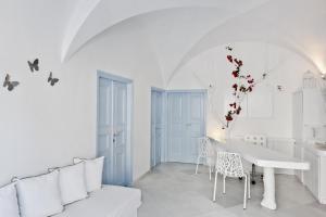 a white kitchen and dining room with a white table and chairs at Casa Florina in Imerovigli