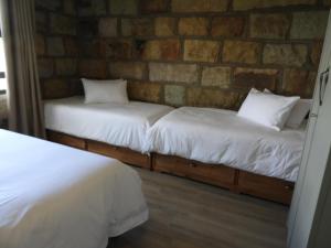 2 Betten in einem Zimmer mit Ziegelwand in der Unterkunft Oranje Guest Farm in Fouriesburg