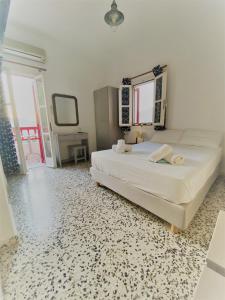 a bedroom with a large white bed with a mirror at Anna Studios in Katapola