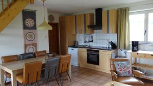 una cucina con tavolo e sedie in legno e tavolo e una cucina con di Appartement Hoeve Espewey - Leisure only a Hombourg