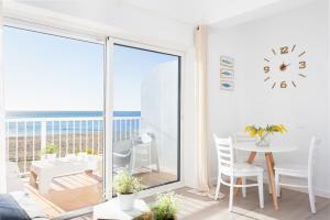 Sala de estar blanca con mesa y vistas al océano en Higuerón Rental Playa Estudio, en Benalmádena