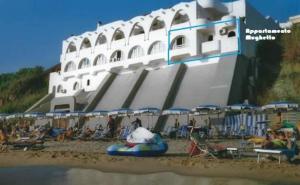 un grande edificio bianco su una spiaggia con sedie e ombrelloni di Casa Vacanze Elianto ad Anzio