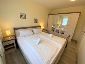 una camera da letto con un grande letto bianco con due asciugamani di Appartmenthaus Witthöhn, Whg. 2 a Cuxhaven