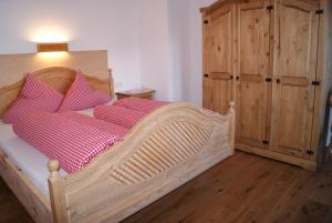 ニーダートハイにあるBichlhofのベッドルーム1室(木製ベッド1台、赤い枕付)