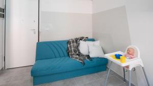 niebieska kanapa w pokoju z lalką w krzesełku do karmienia w obiekcie Babyaccommodation Family Panoramic II w mieście Pietra Ligure +18 zdjęć