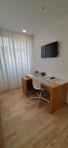 an office with a desk and a television on a wall at Central Suites in São João da Madeira