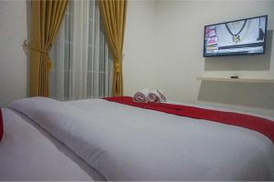 een slaapkamer met een bed en een flatscreen-tv bij RedDoorz near Araya Family Club House in Malang