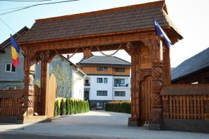 a wooden archway with flags on it in front of a building at Pensiunea Maramures Guesthouse in Vişeu de Jos