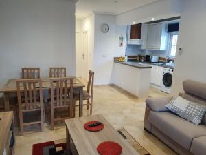 Una sala de estar y una cocina con un sofá y una mesa. en Spacious Ground floor apartment with Garden & Communal Pool, en Los Dolses