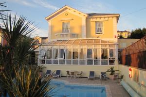 uma grande casa amarela com uma piscina em frente em Riviera Lodge Hotel em Torquay