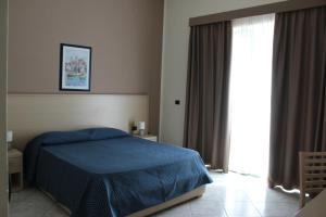 a bedroom with a blue bed and a large window at Hotel Tourist in Cefalù