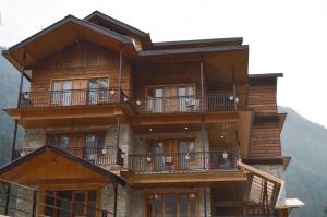 een groot houten gebouw met balkons op een berg bij The Hillside in Kasol