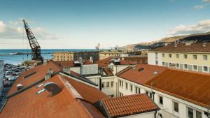uma vista sobre os telhados dos edifícios e o oceano em Hotello Hostel em Trieste