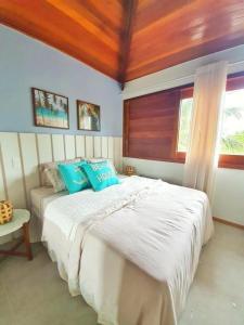 a bedroom with a large white bed with blue pillows at Villagio di Mare in Barra Grande