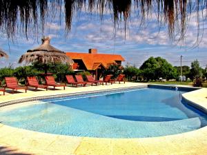 una piscina con sillas y una casa con techo de paja en Cabañas Oma Lissi en Merlo